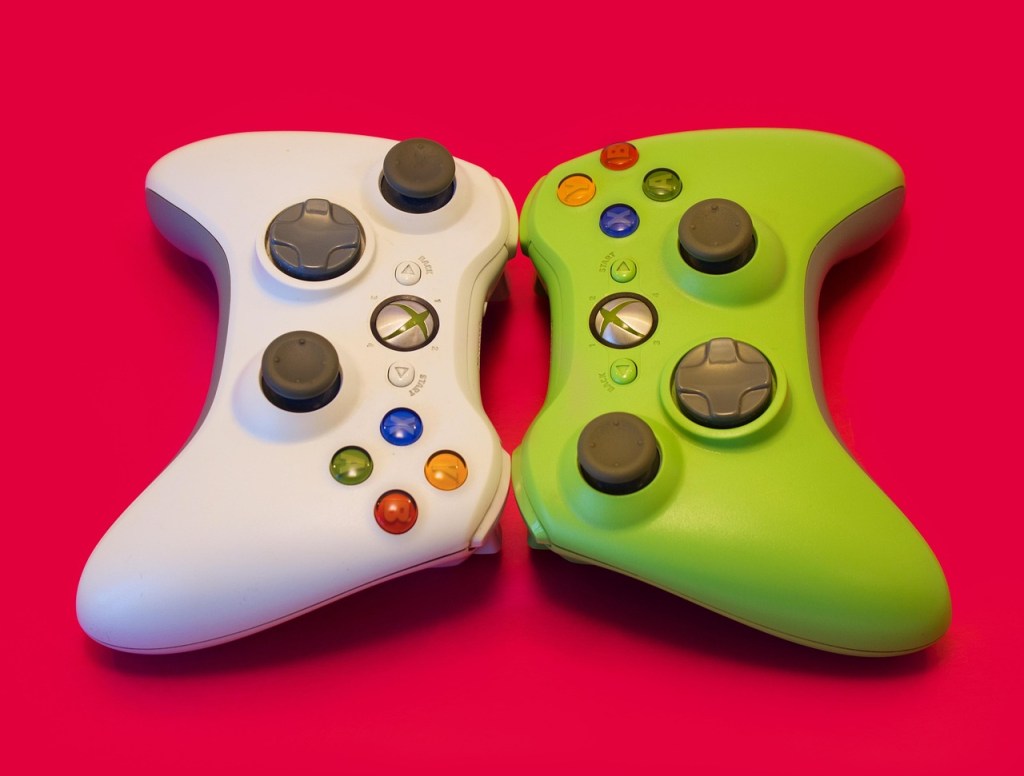 Image of two Xbox 360 wireless controllers flat on a table.